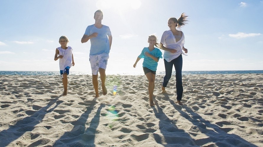 Familie am Strand Junge Familie mit Tochter und Sohn läuft lachend am Strand